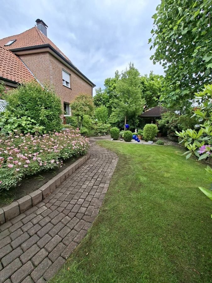 Gepflegter Gartenweg mit Rosenbeet und Rasen